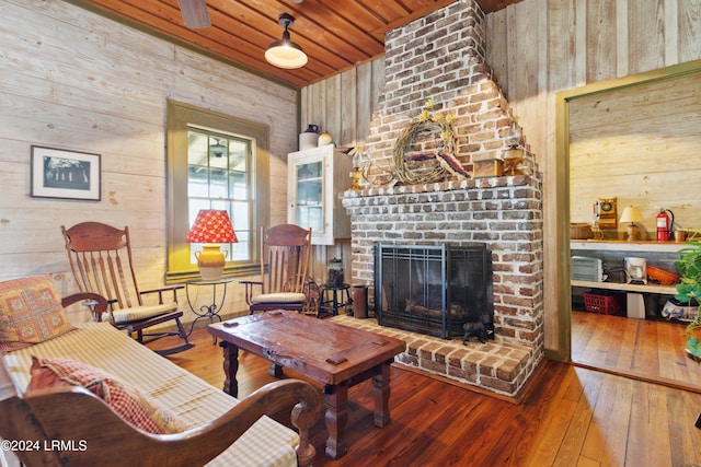 living room with a brick fireplace, wooden ceiling, wooden walls, and hardwood / wood-style floors