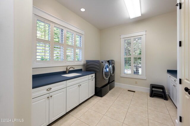 washroom featuring washing machine and dryer, light tile patterned flooring, a sink, and a healthy amount of sunlight