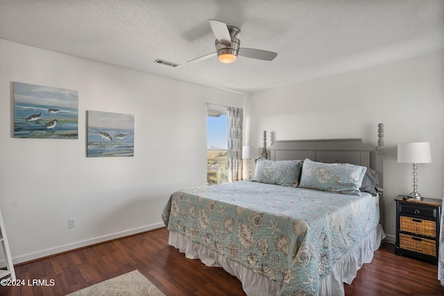 bedroom with dark wood-type flooring, a textured ceiling, and ceiling fan
