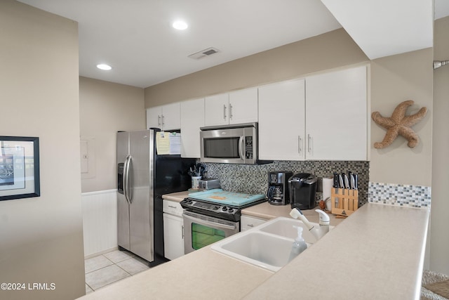 kitchen with light tile patterned flooring, sink, white cabinets, decorative backsplash, and stainless steel appliances