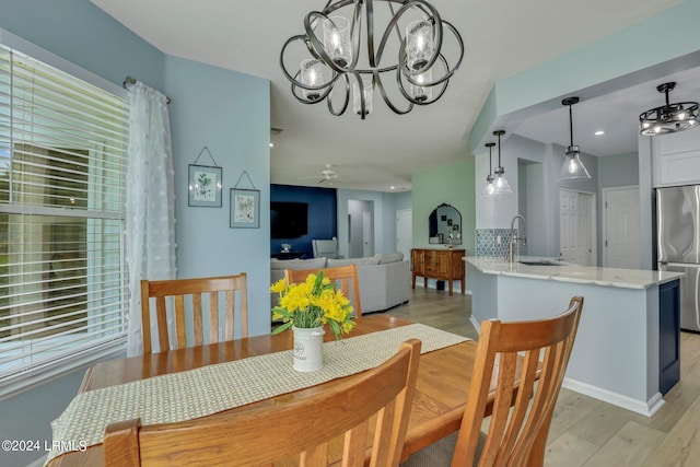 dining space featuring sink, ceiling fan with notable chandelier, and light hardwood / wood-style floors