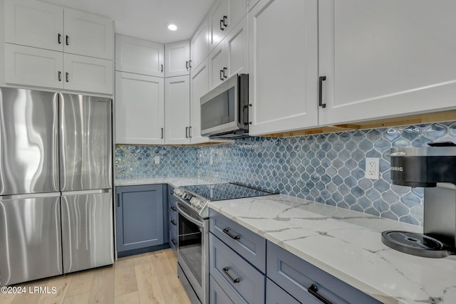 kitchen featuring light hardwood / wood-style flooring, white cabinetry, stainless steel appliances, tasteful backsplash, and light stone countertops