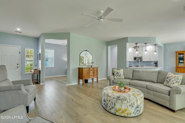 living room with ceiling fan, sink, and light wood-type flooring