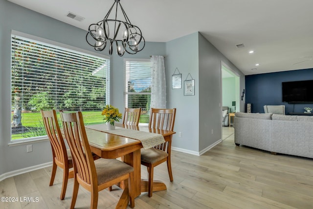 dining area with a wealth of natural light, light hardwood / wood-style flooring, and a chandelier