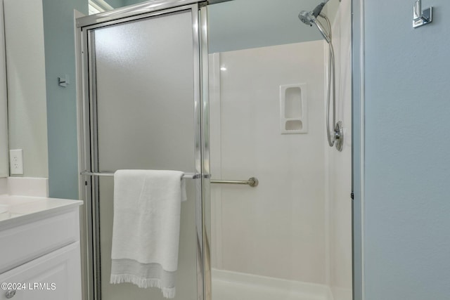 bathroom featuring a shower with door and vanity