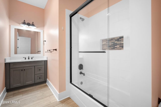 bathroom featuring wood-type flooring, shower / bath combination with glass door, and vanity