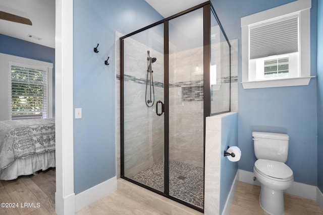 bathroom featuring hardwood / wood-style flooring, a shower with shower door, and toilet