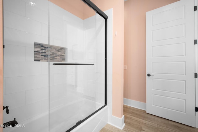 bathroom with enclosed tub / shower combo and wood-type flooring