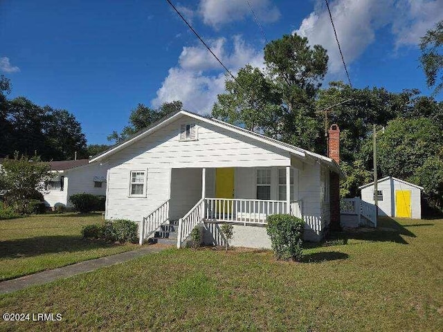 bungalow-style house with a front yard, covered porch, and a shed