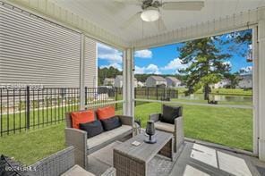 sunroom featuring ceiling fan and a water view