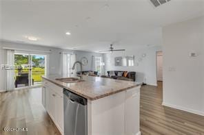 kitchen with sink, dishwasher, an island with sink, white cabinets, and light wood-type flooring