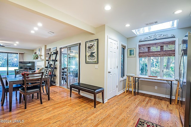 dining room featuring beamed ceiling and light hardwood / wood-style floors