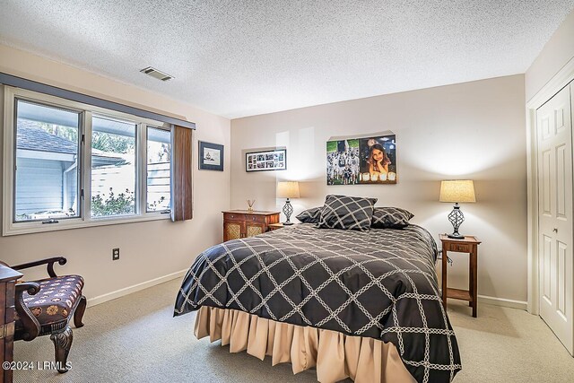 carpeted bedroom featuring a textured ceiling and a closet