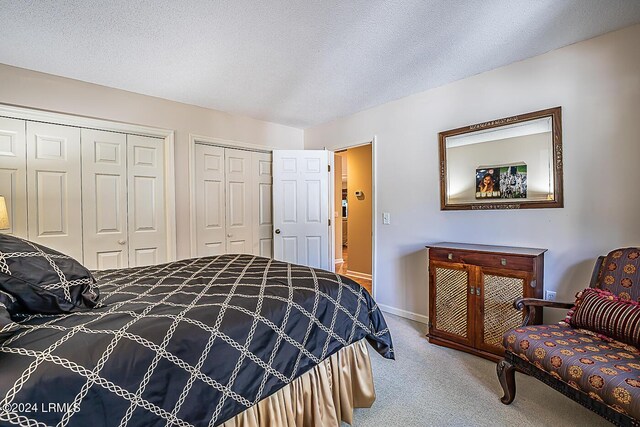 carpeted bedroom with multiple closets and a textured ceiling