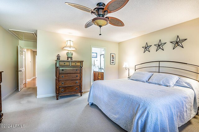 bedroom with light colored carpet, a textured ceiling, ceiling fan, and ensuite bath