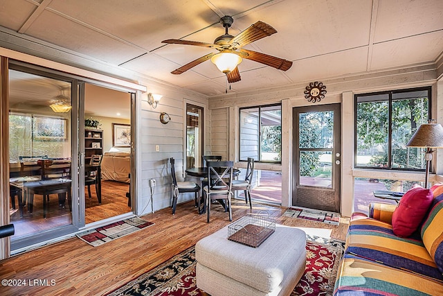 living room with wooden walls, hardwood / wood-style floors, and ceiling fan