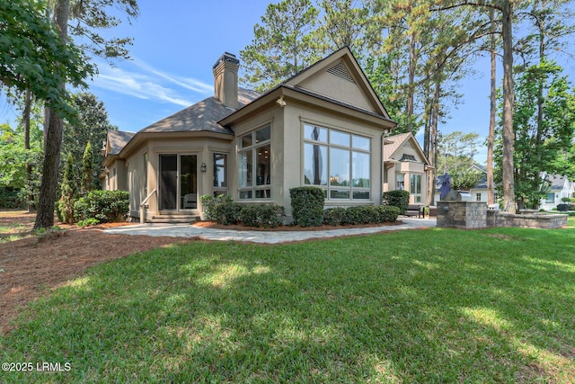 45 Manchester Ct, Bluffton, SC 29910 - rear view of property with stucco siding, a yard, a chimney, and entry steps