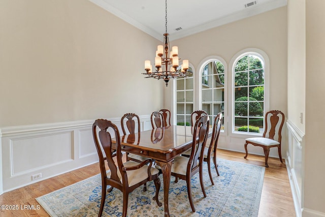 45 Manchester Ct, Bluffton, SC 29910 - dining space featuring a chandelier, crown molding, light wood finished floors, a wainscoted wall, and a decorative wall