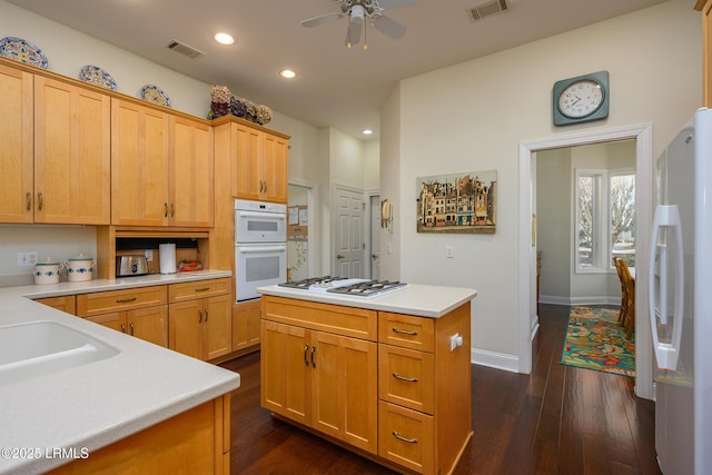 kitchen featuring a kitchen island, sink, ceiling fan, dark wood-type flooring, and white appliances