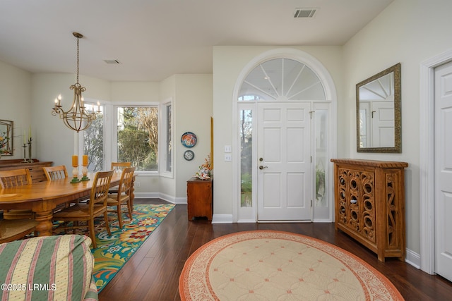 entryway with an inviting chandelier and dark wood-type flooring