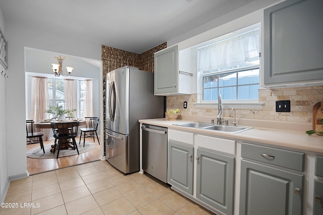 kitchen featuring sink, light tile patterned floors, appliances with stainless steel finishes, gray cabinets, and decorative backsplash