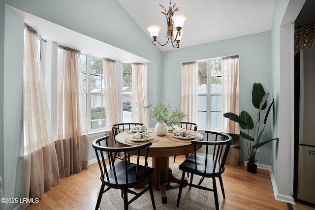 dining space with vaulted ceiling, light hardwood / wood-style flooring, and a notable chandelier