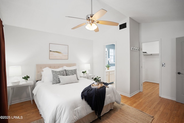 bedroom featuring vaulted ceiling, wood-type flooring, a walk in closet, ceiling fan, and a closet