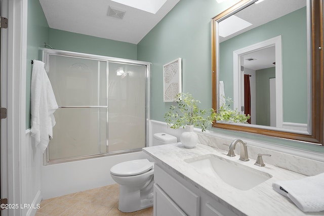 full bathroom featuring bath / shower combo with glass door, a skylight, vanity, toilet, and tile patterned floors