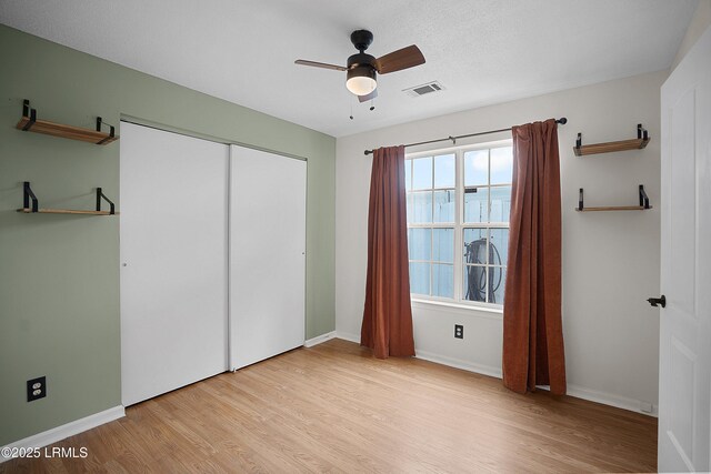 unfurnished bedroom featuring light wood-type flooring, ceiling fan, and a closet