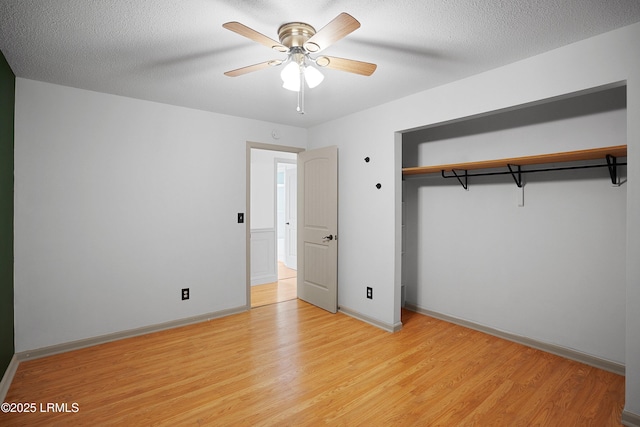 unfurnished bedroom featuring a textured ceiling, a closet, ceiling fan, and light wood-type flooring