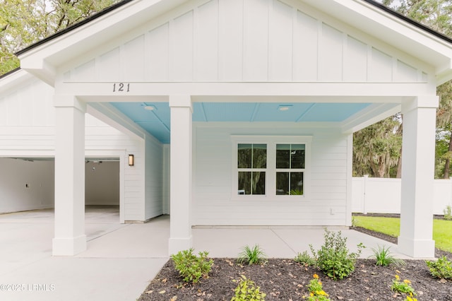 exterior space with a garage, concrete driveway, board and batten siding, and fence