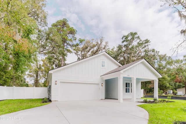 modern farmhouse style home with concrete driveway, an attached garage, fence, board and batten siding, and a front yard