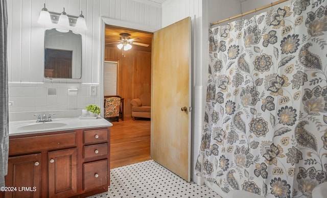 bathroom with vanity, wood walls, ceiling fan, and walk in shower