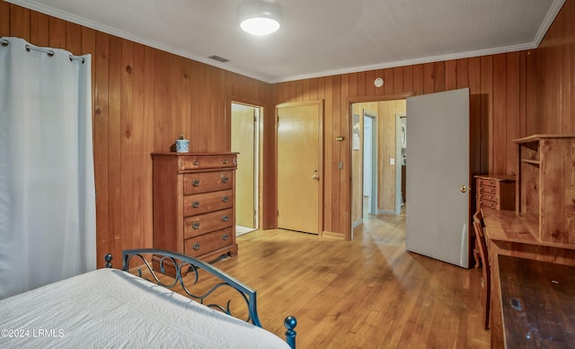 bedroom featuring crown molding, wood walls, and light wood-type flooring