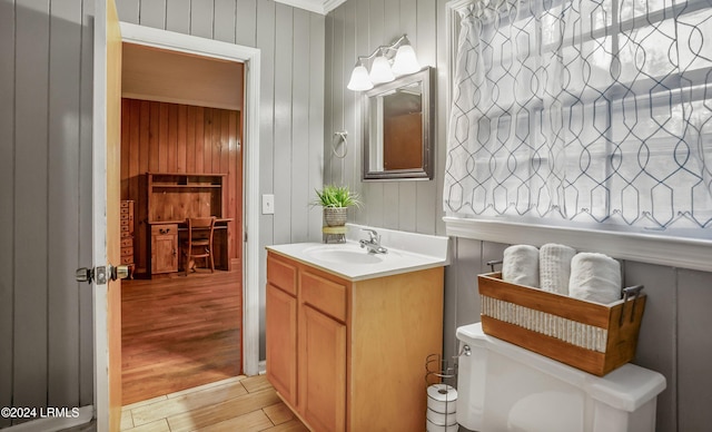 bathroom with vanity, wooden walls, and toilet