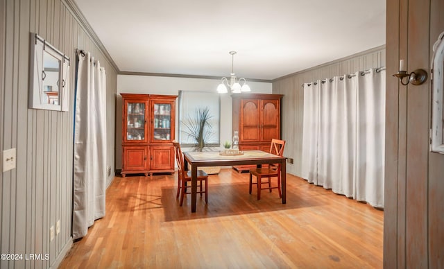 dining space with an inviting chandelier, crown molding, and light hardwood / wood-style flooring