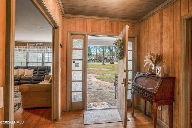 foyer entrance featuring hardwood / wood-style flooring, wood ceiling, ornamental molding, and wood walls