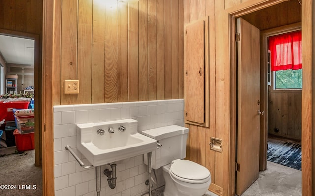 bathroom featuring toilet, sink, and wood walls