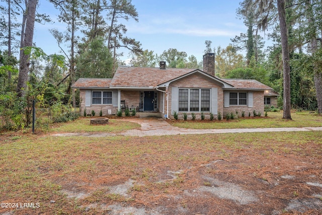 ranch-style home with an outdoor fire pit and a front lawn