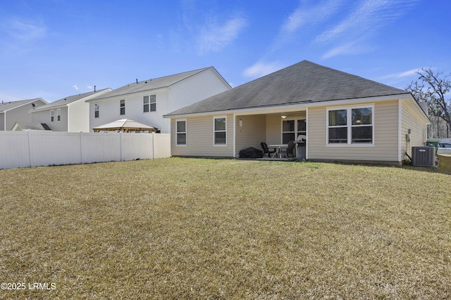 rear view of house featuring a patio area, central AC unit, a lawn, and fence