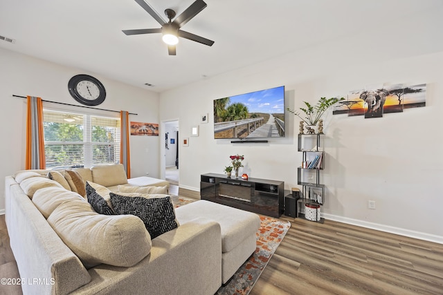 living area featuring visible vents, wood finished floors, baseboards, and ceiling fan