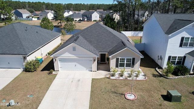 view of front facade with a front lawn, a residential view, roof with shingles, concrete driveway, and a garage