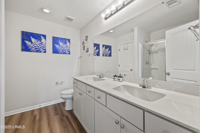 bathroom with a sink, visible vents, wood finished floors, and a stall shower