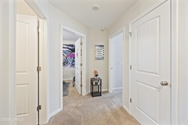 hall with baseboards and light carpet