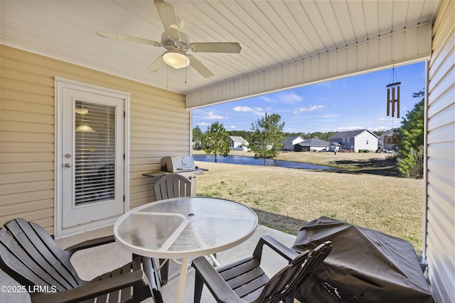 view of patio / terrace featuring grilling area, outdoor dining area, ceiling fan, and a water view