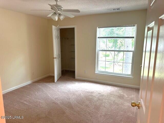 100 Kensington Blvd Unit 1315, Bluffton, SC 29910 - unfurnished bedroom featuring carpet floors, a spacious closet, a textured ceiling, ceiling fan, and a closet