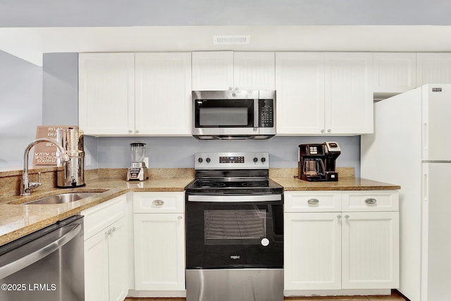 kitchen featuring white cabinetry, sink, stainless steel appliances, and light stone countertops