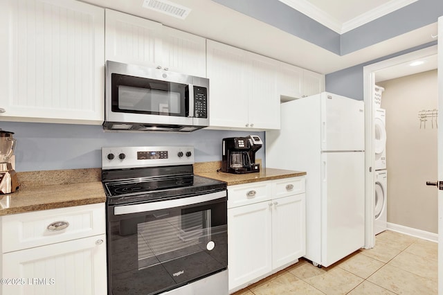 kitchen featuring appliances with stainless steel finishes, stacked washer / dryer, white cabinetry, ornamental molding, and light tile patterned floors