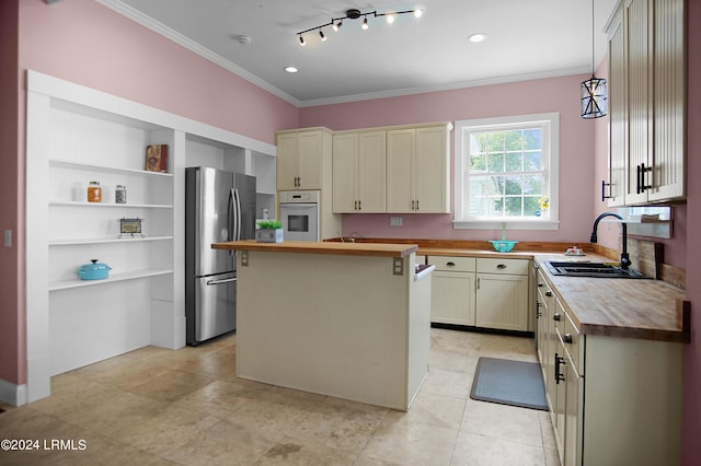 kitchen with butcher block countertops, ornamental molding, stainless steel fridge, a kitchen island, and white oven