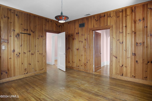 unfurnished room with ornamental molding, wood-type flooring, and wooden walls